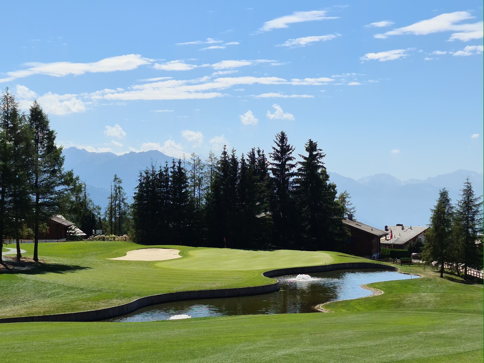 A mountain golf course fairway framed by snow capped peaks