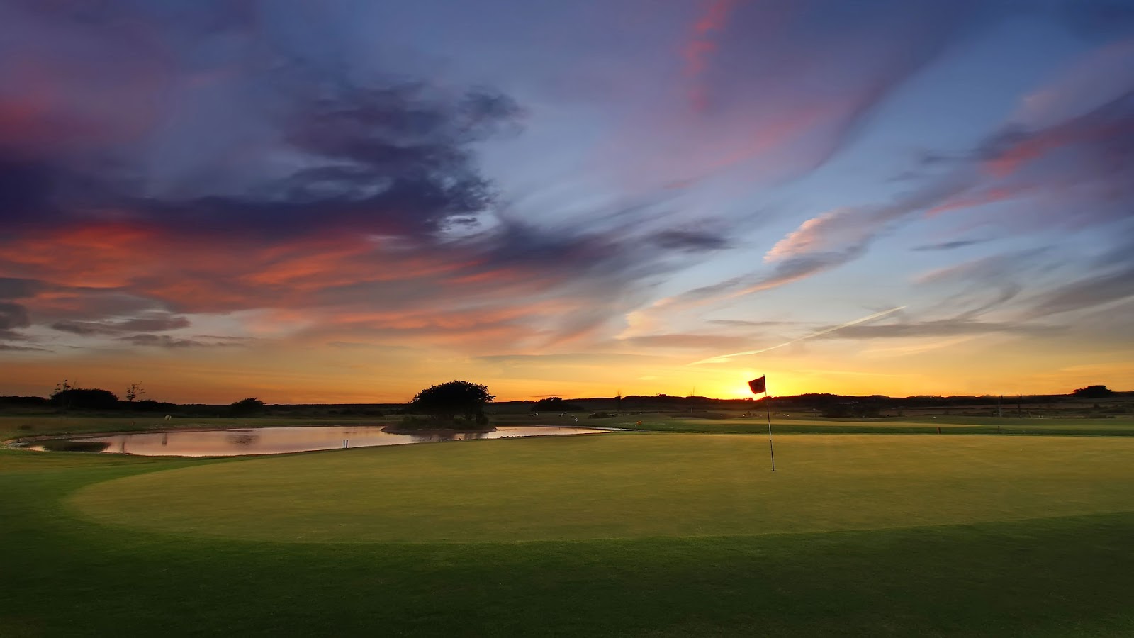 Tramore Golf Club at sunset, a flag on the green beside the water, County Waterford